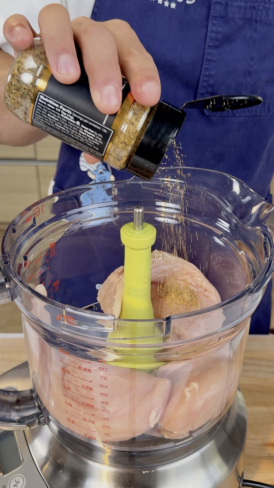 Nick holds Osmo Golden Gourmet Blend beside the chicken in the food processor.