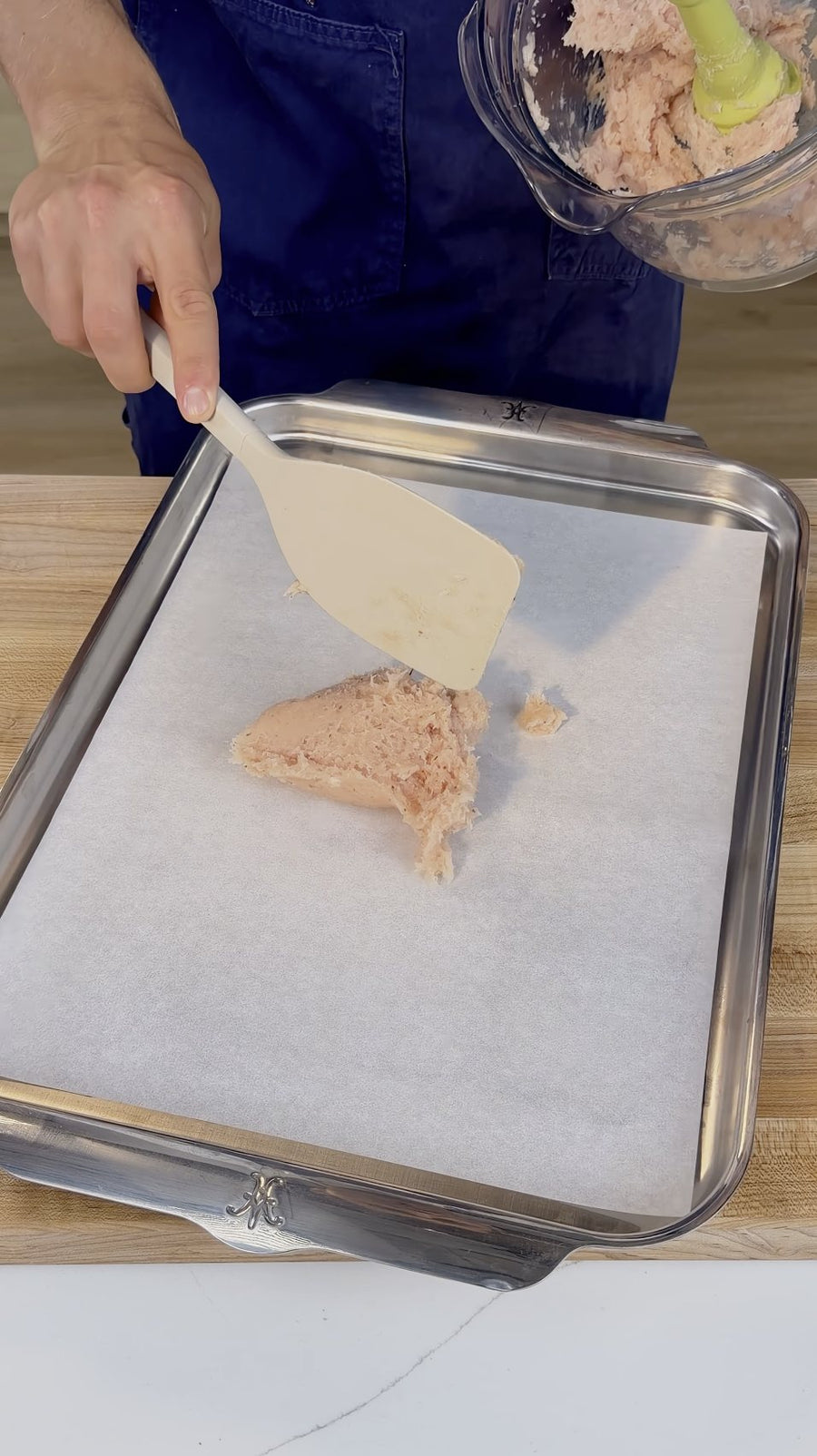 Nick uses a spatula to spread chicken paste onto the lined tray.