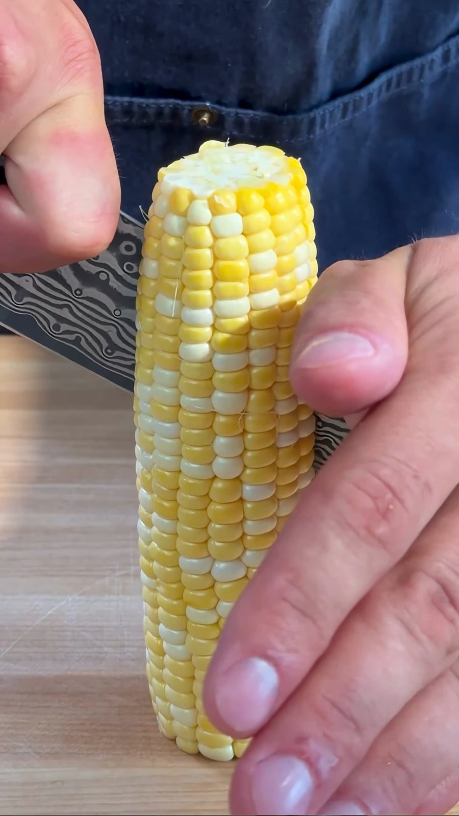 Nick carefully cuts a softened corn cob lengthwise.