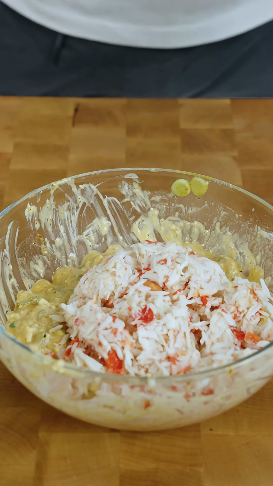 Shredded crab meat sits on the cream cheese mixture, ready to be folded through.