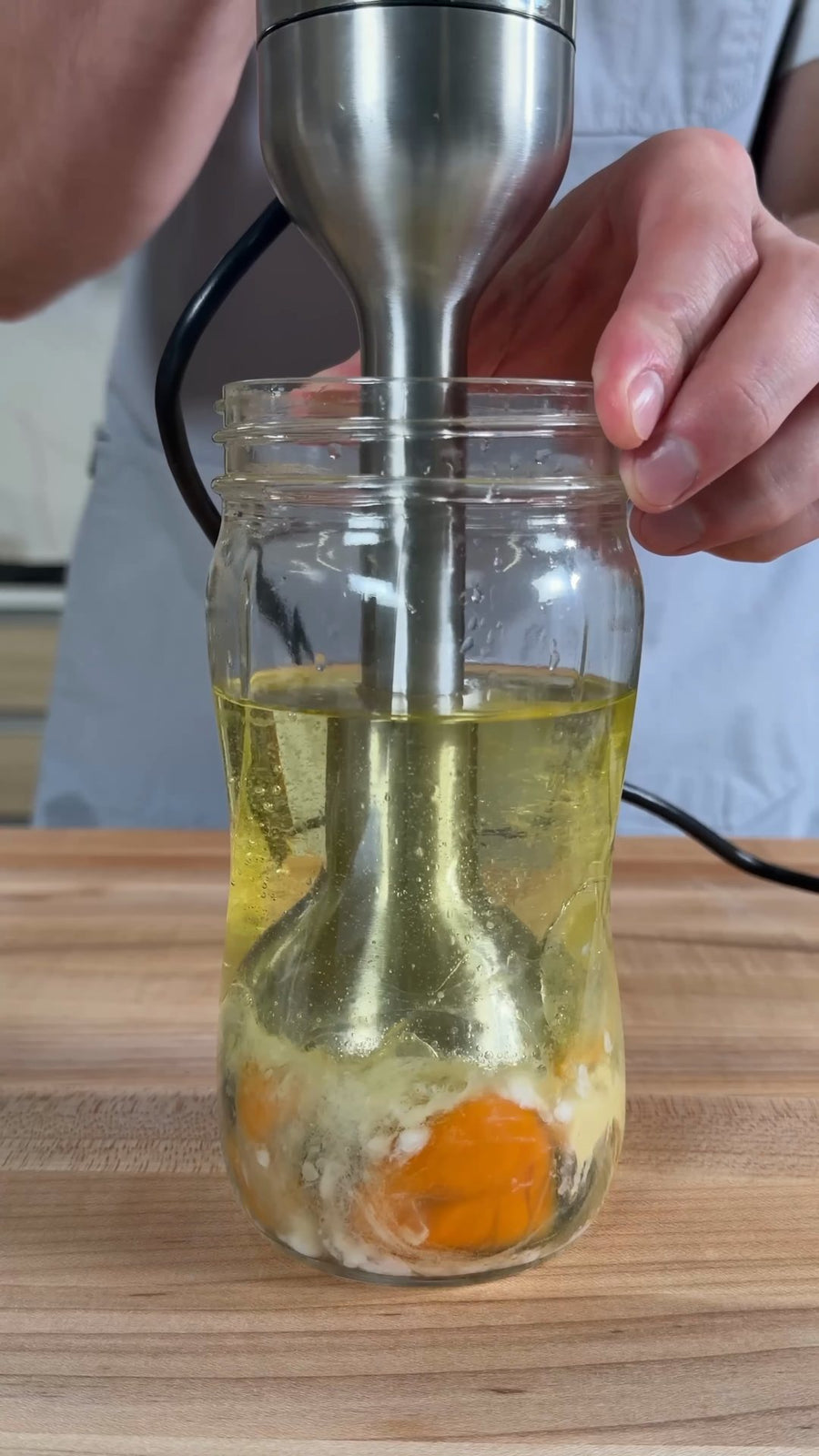 Nick rests the immersion blender at the bottom of the jar.